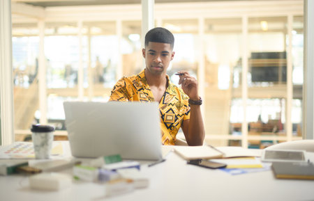 Coming up with some ground-breaking creative ideas. a young businessman working on a laptop in an office.の写真素材