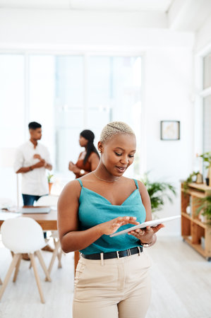 Creating great designs doesnt always need a desk. a young businesswoman using a digital tablet in a modern office.の写真素材