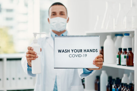 Keep your hands clean. a scientist holding a sign with wash your hands on it and hand sanitiser in a laboratory.の写真素材