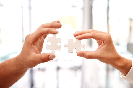 Where there are problems, we should come together to solve it. Closeup shot of two unrecognisable businesspeople holding puzzle pieces together.の写真素材
