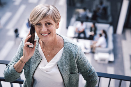 Ill see you at the top. a mature businesswoman using a smartphone on the stairs of a modern office.の写真素材