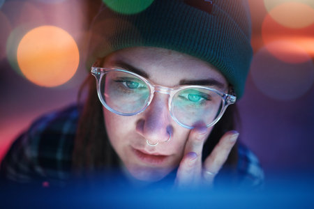 Coding, face and serious woman working overtime at night programming a computer, website or app development. Focus. workaholic and young female student or web design freelancer with a deadlineの写真素材