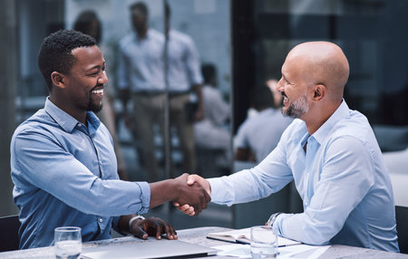 Merge with people who match your ambition. two businessmen shaking hands during a meeting.の写真素材