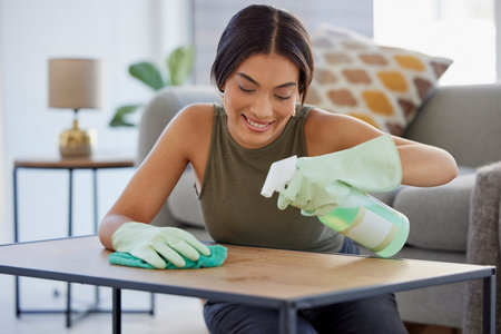 Woman, detergent and smile for cleaning table, hygiene or sanitary wiping in the living room at...