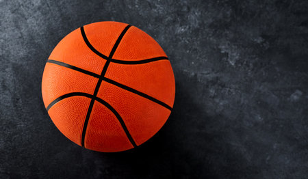 The ball is in your court. High angle shot of a single basket ball placed on top of a dark background inside of a studio.の写真素材