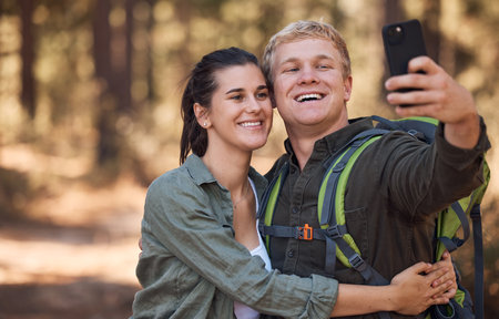 Couple, phone selfie and hiking in nature on holiday or summer vacation. Travel, man and woman enjoying quality time together with 5g mobile smartphone on social media, picture post or happy memory.の写真素材