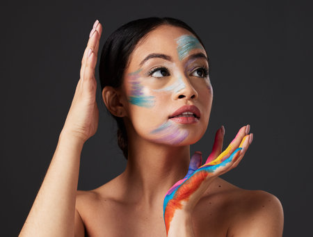 Beauty, art and woman with paint on face and hands, creative makeup and self expression. Aesthetic, creativity and artistic color cosmetics, skincare and freedom to express for young beautiful girl.の写真素材