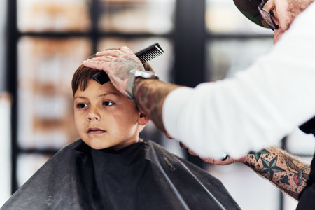 Everyone will be chatting about my cool hairstyle at school. Cropped shot an adorable little boy getting a haircut at the barbershop.の写真素材