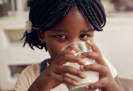 Im just getting my daily dose of calcium. Portrait of an adorable little girl drinking a glass of milk at home.の写真素材