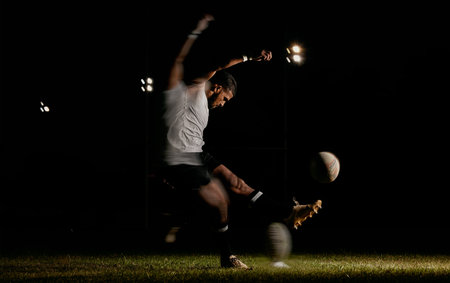 Rugby, night and man kicking ball to score goal at dark stadium at game, match or practice workout. Sports, fitness and motion, player with blurred action on grass with energy and skill in team sportの写真素材
