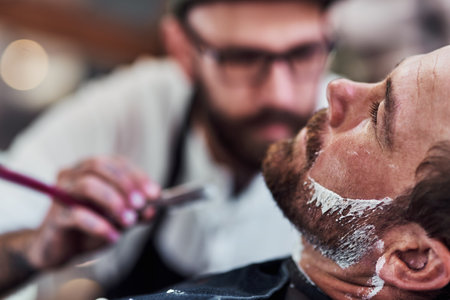 Im ready for beard season. a handsome mature man getting his beard trimmed and lined up at a barbershop.の写真素材