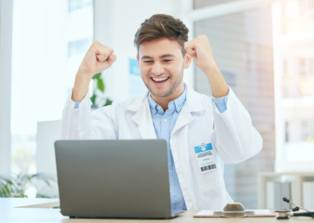 Success, medical and laptop with doctor in hospital and cheering for celebration, report or achievement. Winner, research and technology with man reading good news for healthcare, medicine or scienceの写真素材