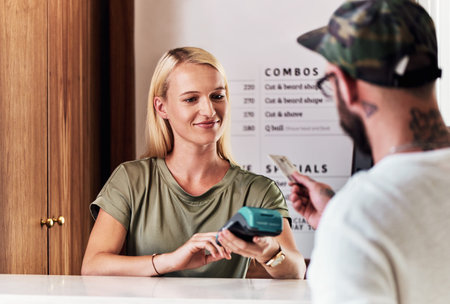 The convenient way of making payment. an attractive young hairdresser using a credit card machine to...