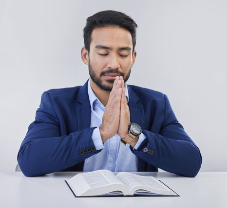 Mockup, faith and Asian man, praying, bible and guidance against grey studio background. Japanese male, believer and Christian guy with holy book, prayer and hope for solution, religious or gratitudeの写真素材