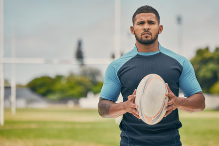 Rugby, field and portrait of man with ball, serious expression and confidence in winning game. Fitness, sports and player training for match, workout or competition on grass at stadium with mockup.の写真素材