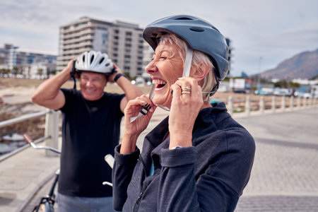 Helmet, laughter and a senior couple cycling outdoor together for fitness or an active lifestyle. Summer, exercise or humor with a mature man and woman laughing on the promenade during summerの写真素材