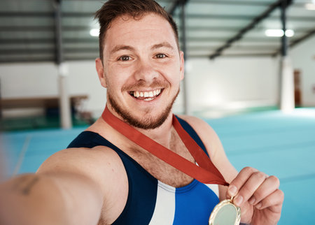 Gymnastics, fitness and male athlete taking a selfie after winning a medal in competition. Sports, smile and portrait of happy male gymnast winner taking a picture after training or practice in arenaの写真素材