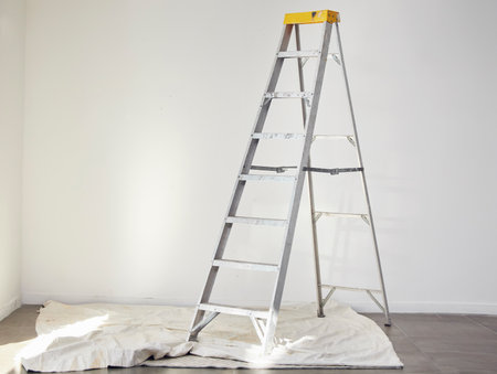 Ladder, room interior and home renovation project for wall painting or repair with no people. Isolated, property development and apartment building diy with sheet for paint process in a houseの写真素材