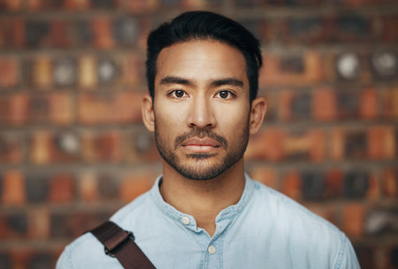 Serious, confidence and portrait of a businessman in the office standing by a brick wall. Pride, professional and face of an Indian corporate male employee or expert with success in modern workplace.の写真素材