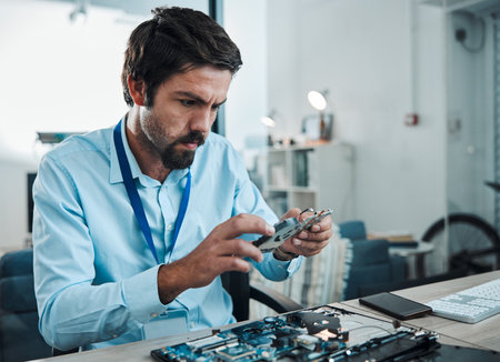Man, circuit and hard drive in repair workshop for maintenance, computer tech or industry with focus. Technician, motherboard and information technology at desk for electronics, engineering and toolsの写真素材