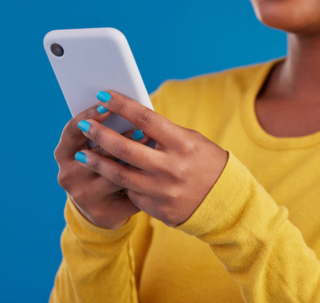 Phone, typing and closeup of hands of woman in studio for social media, text message and browse...
