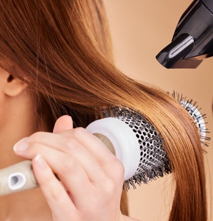 Hair, closeup and woman with hairdryer in studio for beauty, blowing and styling on brown background. Zoom, haircare and girl with salon treatment, hairstyle and hairdressing appliance isolatedの写真素材