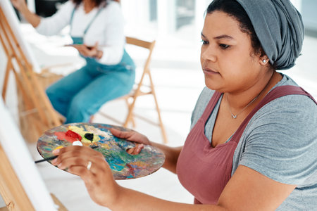 Art is like a form of therapy. an attractive young woman sitting with her friends and painting during an art class in the studio.の写真素材
