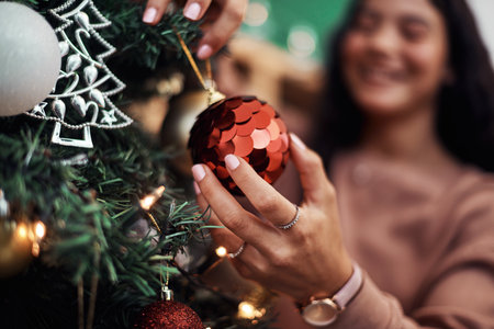 The season of all things sparkly. a young woman decorating a Christmas tree at home.の写真素材