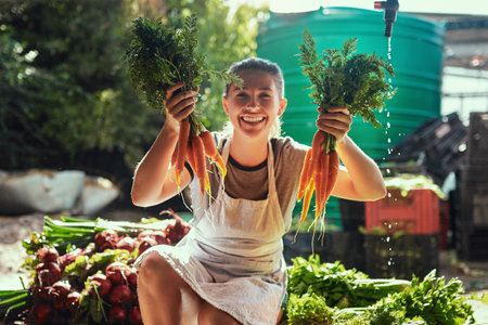 Nature always gives you more than you bargained for. Portrait of an attractive young female farmer holding a bunch of freshly picked carrots at her farm.の写真素材