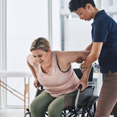Shes helping me get back on my feet again. a young physiotherapist doing exercises with her wheelchair bound patient inside her office at a clinic.の写真素材