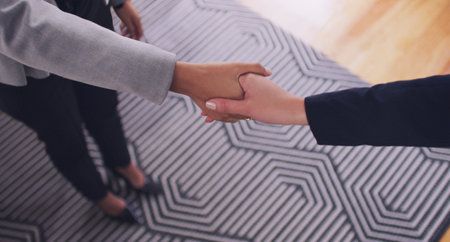 Im very pleased to meet you. High angle shot of an unrecognizable female financial advisor shaking hands with a client in her office during the day.の写真素材