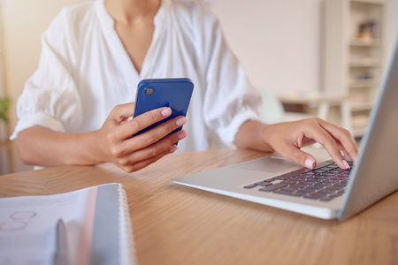 Phone, laptop and search with hands of woman in office for social media, networking and connection. Internet, technology and planning with female for contact, communication and browsing onlineの写真素材