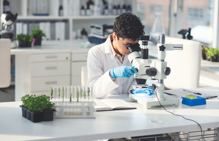 Take a look theres a lot to discover. an attractive young female scientist looking through a microscope while working with plants in a laboratory.の写真素材