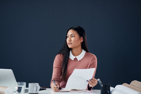 Creativity can strike at anytime. an attractive young female architect going over paperwork and designs in her office.の写真素材