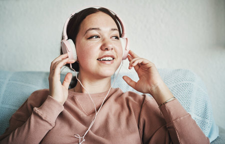 Its always a good time for music. an attractive young woman sitting on her home sofa alone and...