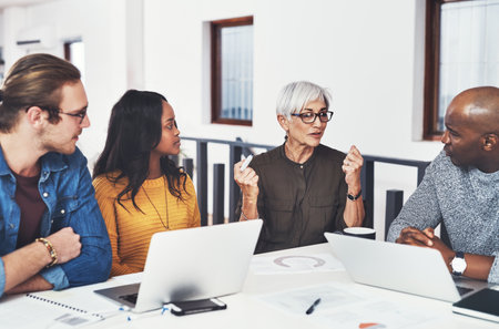 She loves to take charge in the company. a group of confident businesspeople having a meeting together inside of the office during the day.の写真素材