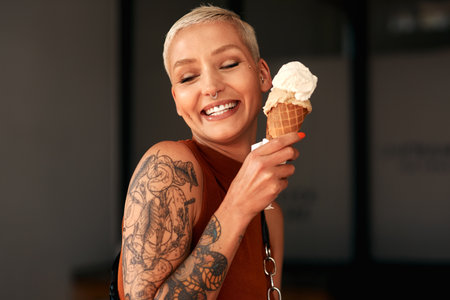 Ice cream takes me back to my childhood. a young woman enjoying a ice cream cone outdoors.の写真素材