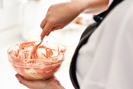 This will be the icing on the cake. an unrecognizable woman mixing icing in a glass bowl.
