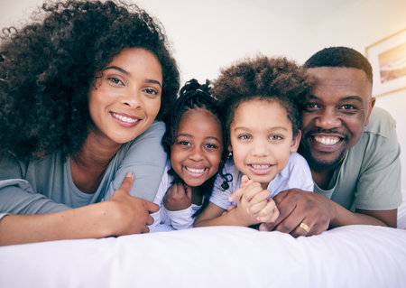 Black family smile, happiness and portrait of a mother, father and girl children on a house bed. Bedroom, home and happy kids with parent love and support from mama and dad together in the morningの写真素材