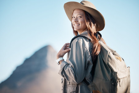 Hiking woman, portrait and smile by mountain, summer or explore with backpack, excited or happy for...