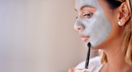 Woman brush clay makeup on face, mask and detox beauty benefits with mockup wall space. Young female apply charcoal skincare product, facial cosmetics and aesthetic cleaning for dermatology wellnessの写真素材
