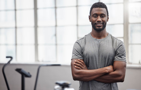 Happy black man smile in gym with arms crossed for training, exercise or workout in Nigeria. Portrait of strong bodybuilder, personal trainer and male in fitness club for coaching, sports or wellnessの写真素材