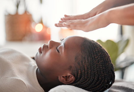 Relax, reiki and black woman with lying at spa for spiritual chakra therapy and alternative medicine. Healing, balance and zen, person with peaceful mindset and healthy mind at traditional massage.の写真素材