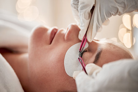 Eyelash extensions, beauty and woman getting a treatment at a salon for cosmetics or self care. Cosmetology, beautiful and young female getting a luxury cosmetic eye procedure from beautician at spa.の写真素材