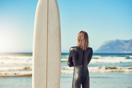 I always take the scenic route. a handsome young man at the beach with his surfboard.の写真素材
