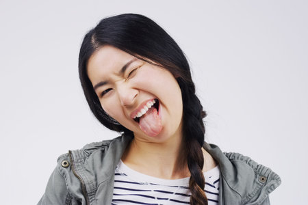 Just kidding. Studio shot of a young woman making a funny face against a gray background.の写真素材