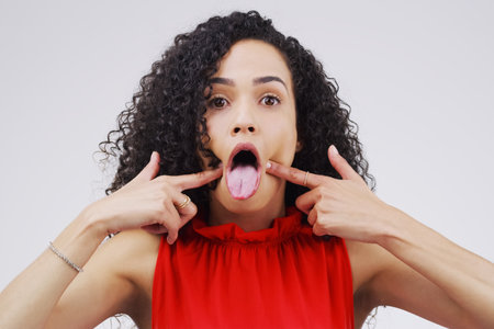 Me after Ive eaten something spicy. Studio shot of a young woman making a funny face against a gray background.の写真素材