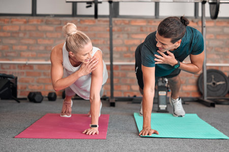 Fitness, push up and woman with partner, personal trainer or gym coach for support, teamwork and muscle goals. Athlete, sports and couple of friends in strong workout, exercise or training togetherの写真素材