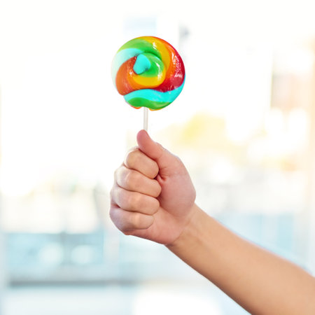 The best weapon to carry in times of distress. an unrecognizable young child holding a lollipop sucker at home.の写真素材
