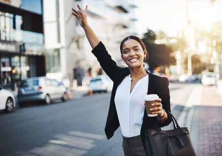 Catching a cab to another great opportunity. a young businesswoman gesturing for a cab in the city.の写真素材